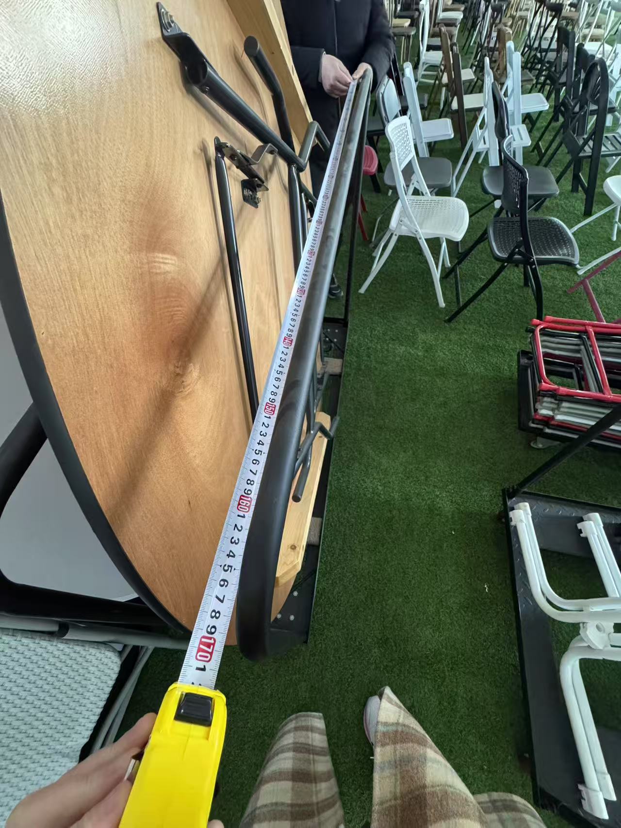 Measuring the depth of the round table trolley frame with a tape measure