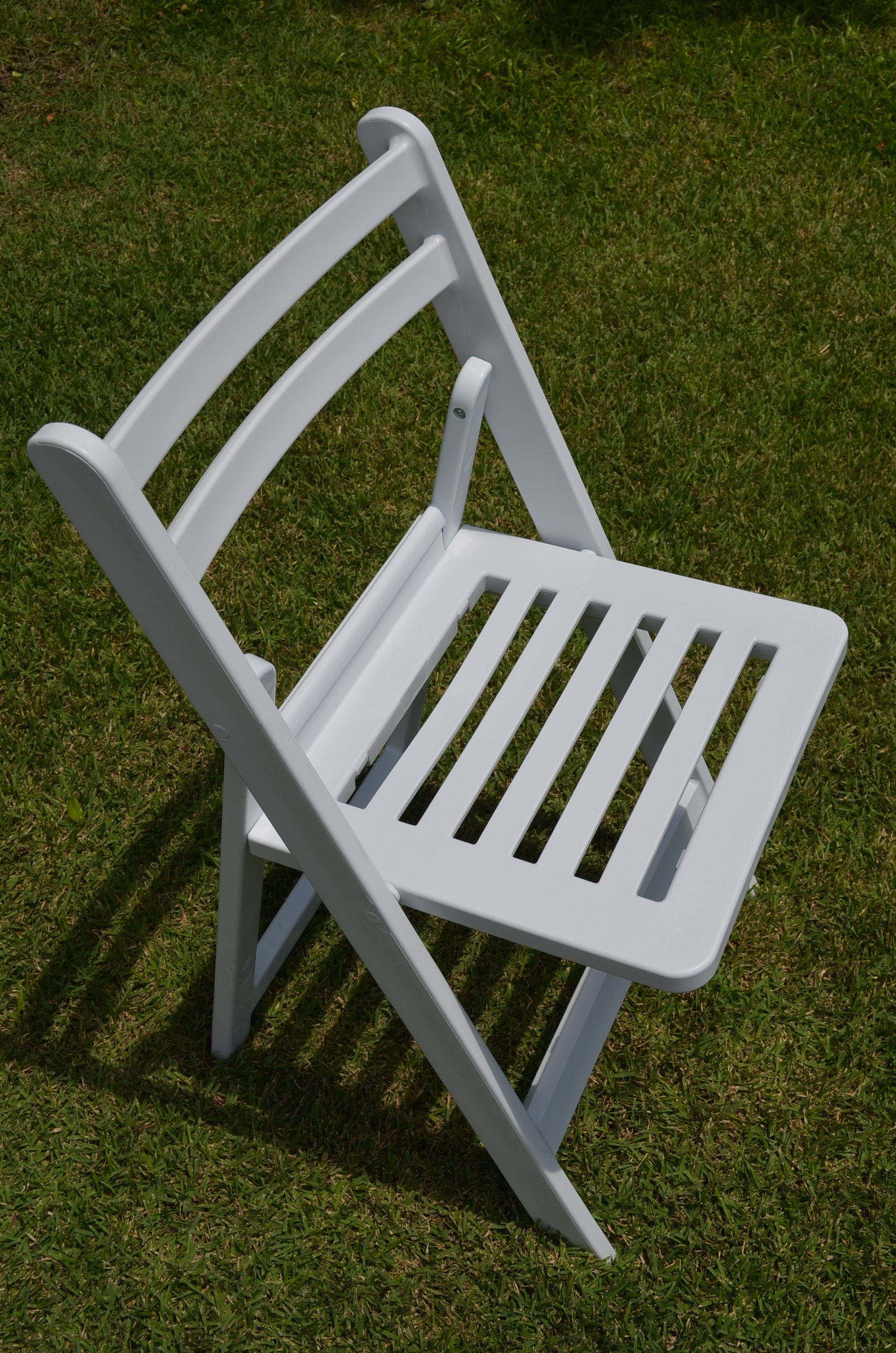 White Americana resin folding chair on grass